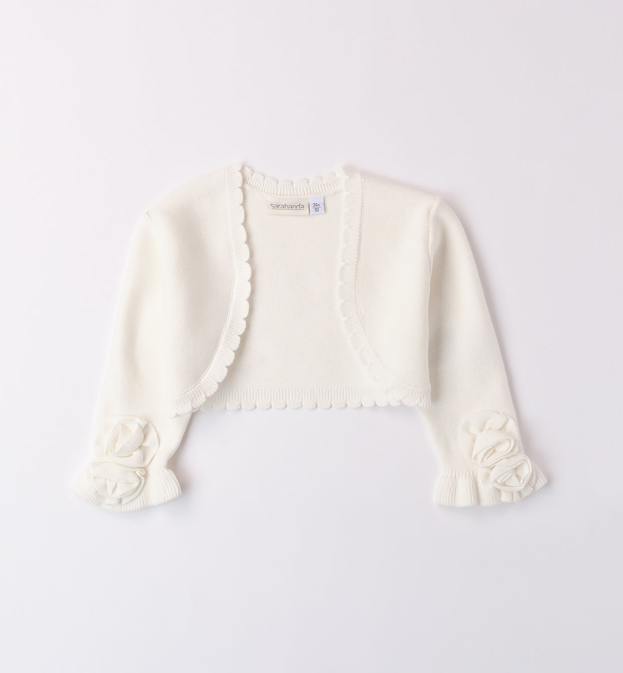 Coprispalle in maglia bianca per bambina con fiori decorativi sulle maniche.

