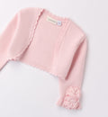 Coprispalle rosa cipria in maglia per bambina con dettagli floreali e bordo smerlato.