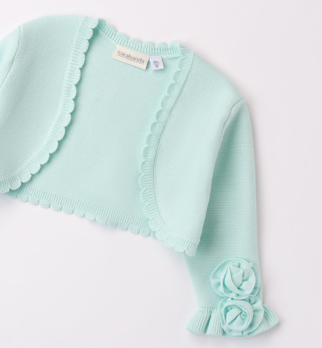Coprispalle bambina in maglia verde acqua con fiori applicati e bordo smerlato.