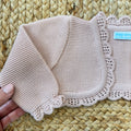 Coprispalle battesimo rosa in maglia con lavorazione traforata, perfetto per neonate.
