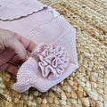 Dettaglio maniche con balze e decorazione floreale sul coprispalle bimba in maglia rosa antico.