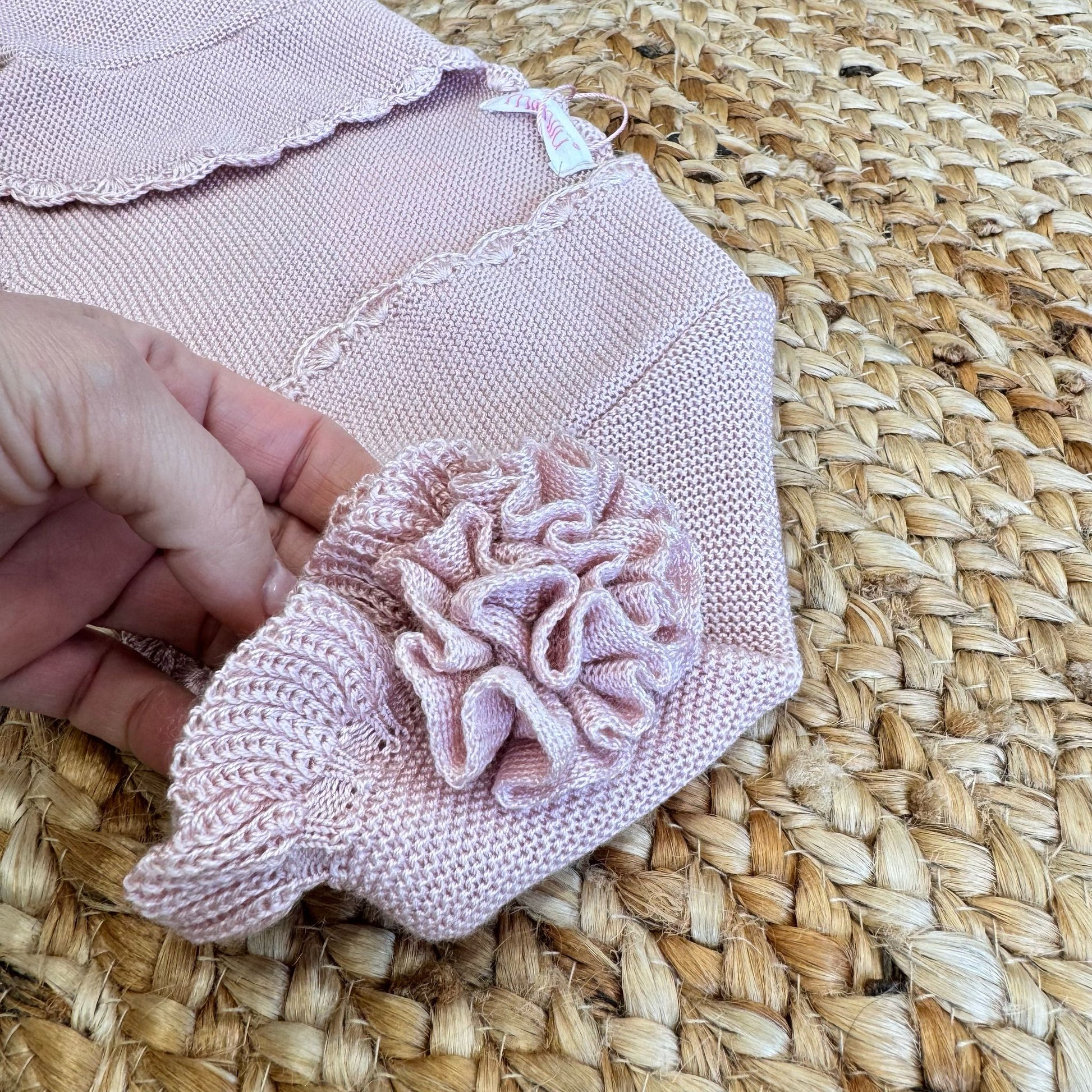 Dettaglio maniche con balze e decorazione floreale sul coprispalle bimba in maglia rosa antico.