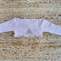 Dettaglio del coprispalle battesimale rosa antico con bordi in pizzo e maniche lunghe