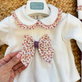 Uscita clinica neonata in ciniglia bianco panna e prugna con tutina, copertina sfoderabile, bavetta, cappellino, scarpine e lenzuolino coordinati.