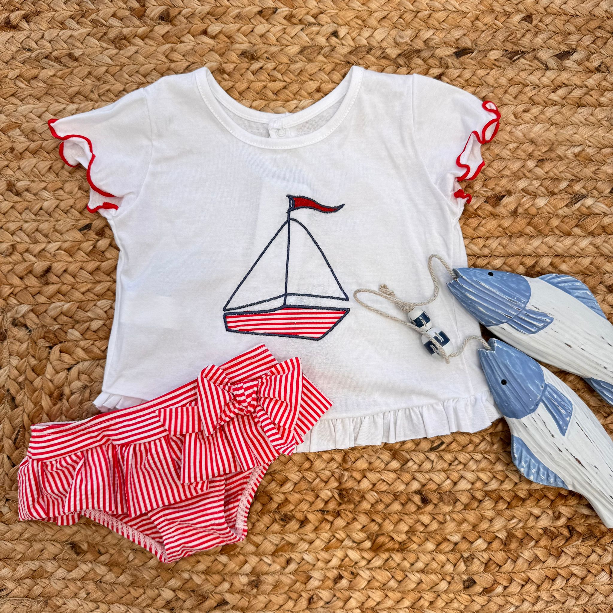 Costume slip a righe rosse con fiocco e t-shirt con stampa barchetta per bambina.


