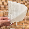 Cuffietta battesimo bimba bianca con pizzo floreale ricamato e laccetti in raso.
