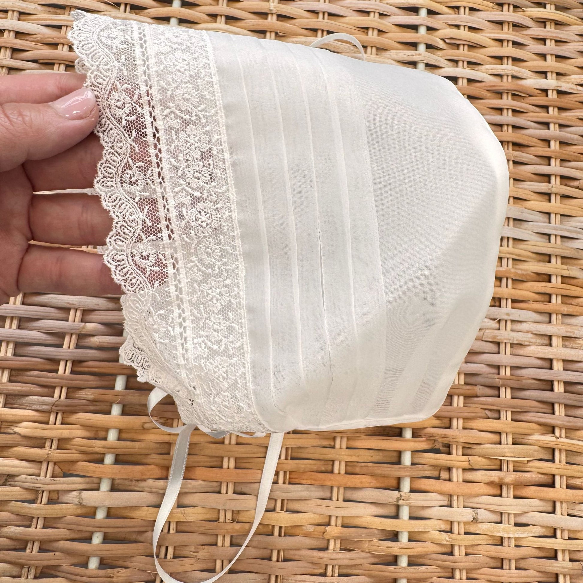 Cuffietta battesimo bimba bianca con pizzo floreale ricamato e laccetti in raso.