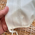 Cuffietta battesimale unisex bianca con ricamo decorativo e laccetti in raso.