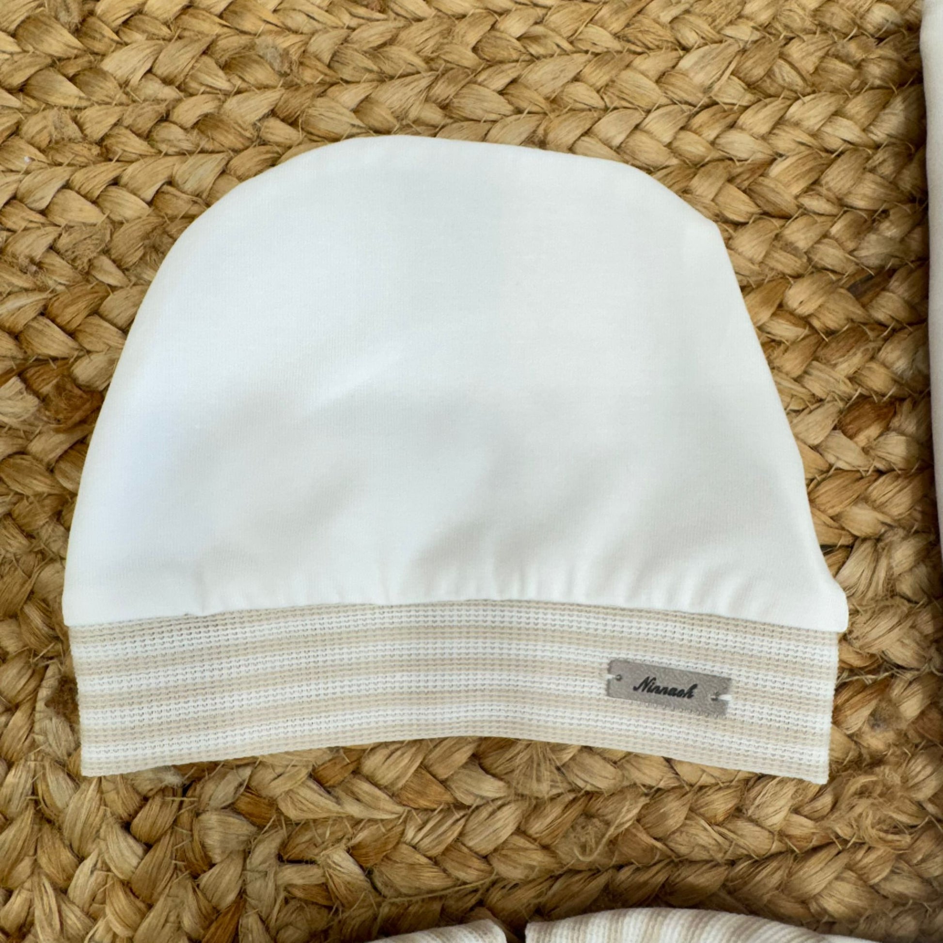 * Cappellino nascita per bebè in cotone bianco con fascia a righe orizzontali beige.