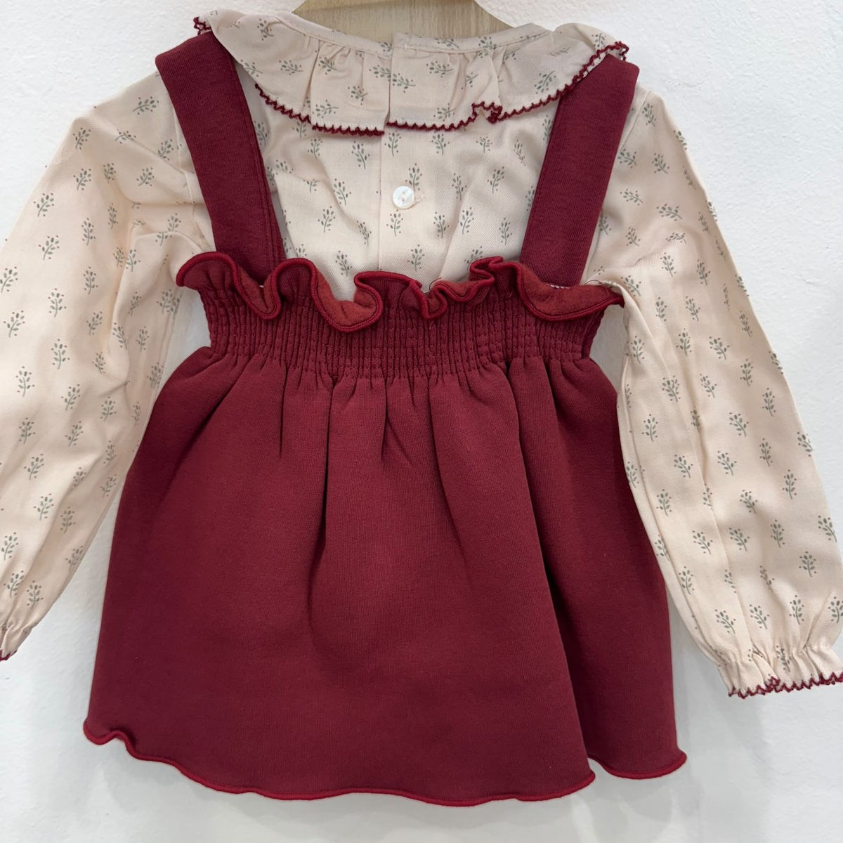 Dettaglio del colletto arricciato della camicetta panna con fantasia floreale e bordino bordeaux.