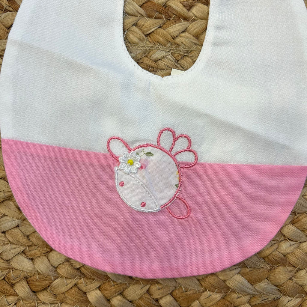 Dettaglio fiore ricamato su bavaglino rosa per neonata