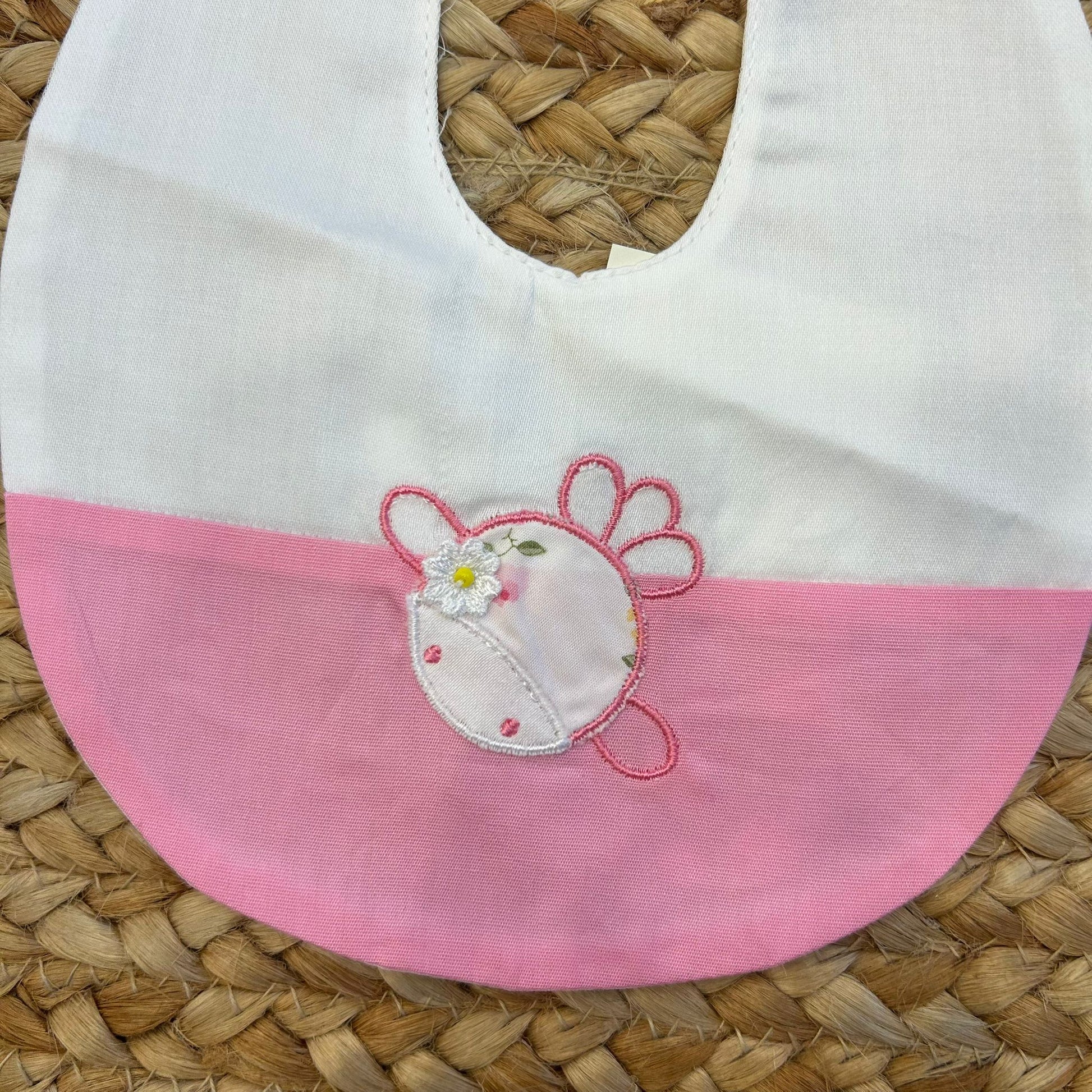 Dettaglio fiore ricamato su bavaglino rosa per neonata