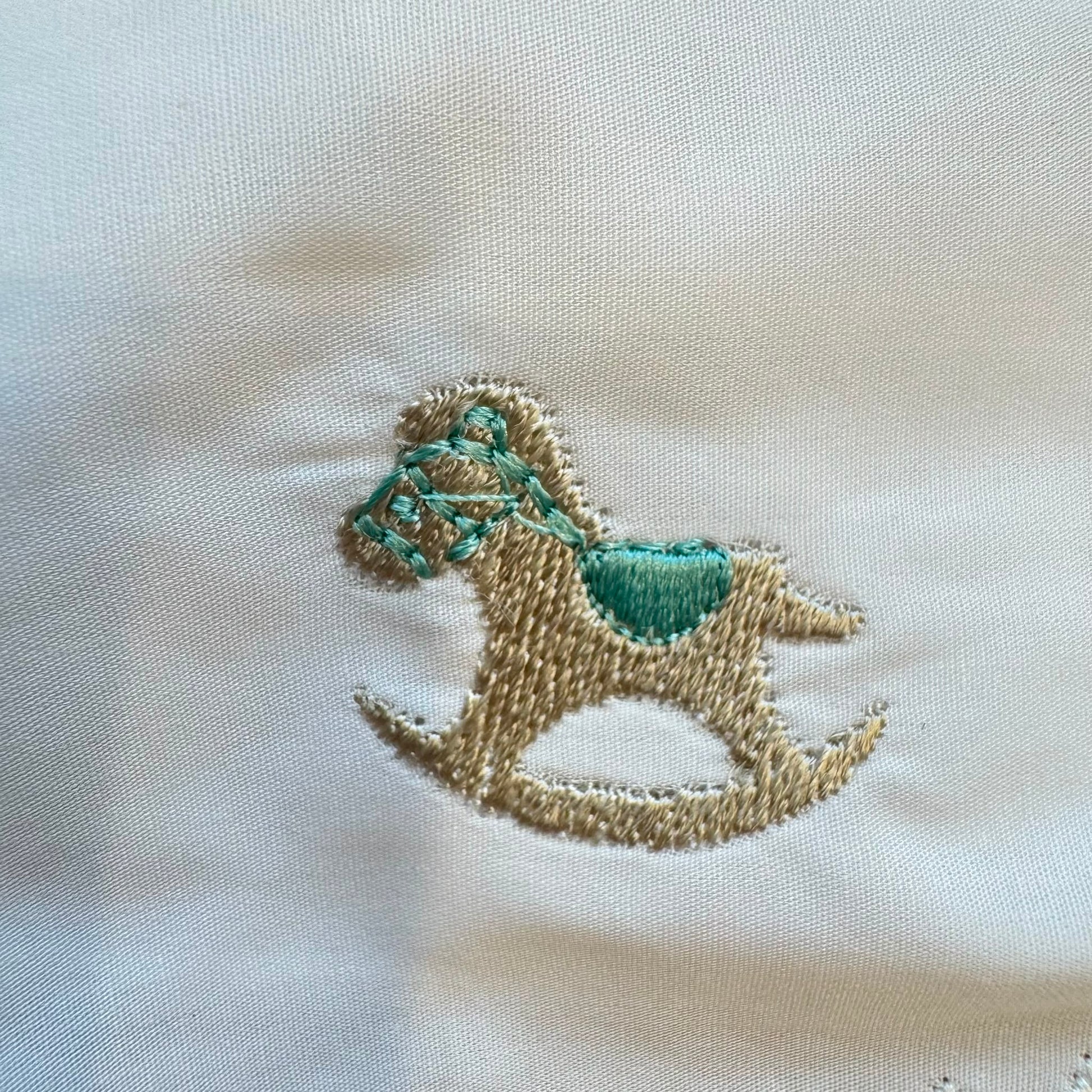 Bavaglino neonato in 100% cotone bianco con ricamo cavallino e bordo smerlato elegante.