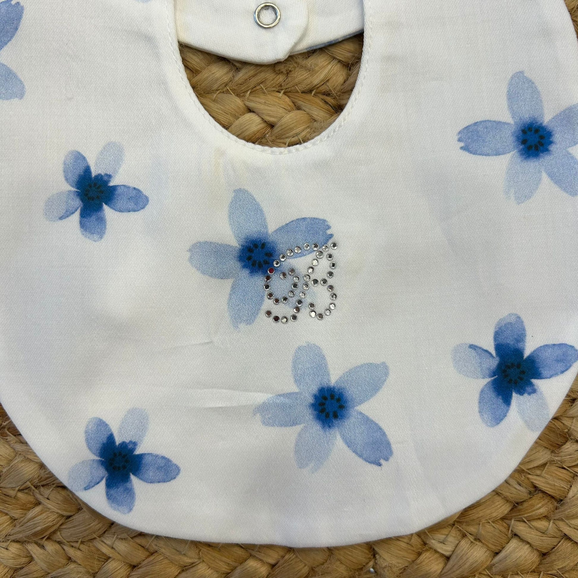  Dettaglio bavaglino in cotone con fiori azzurri e strass