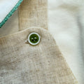 Dettaglio bottone verde su salopette in lino