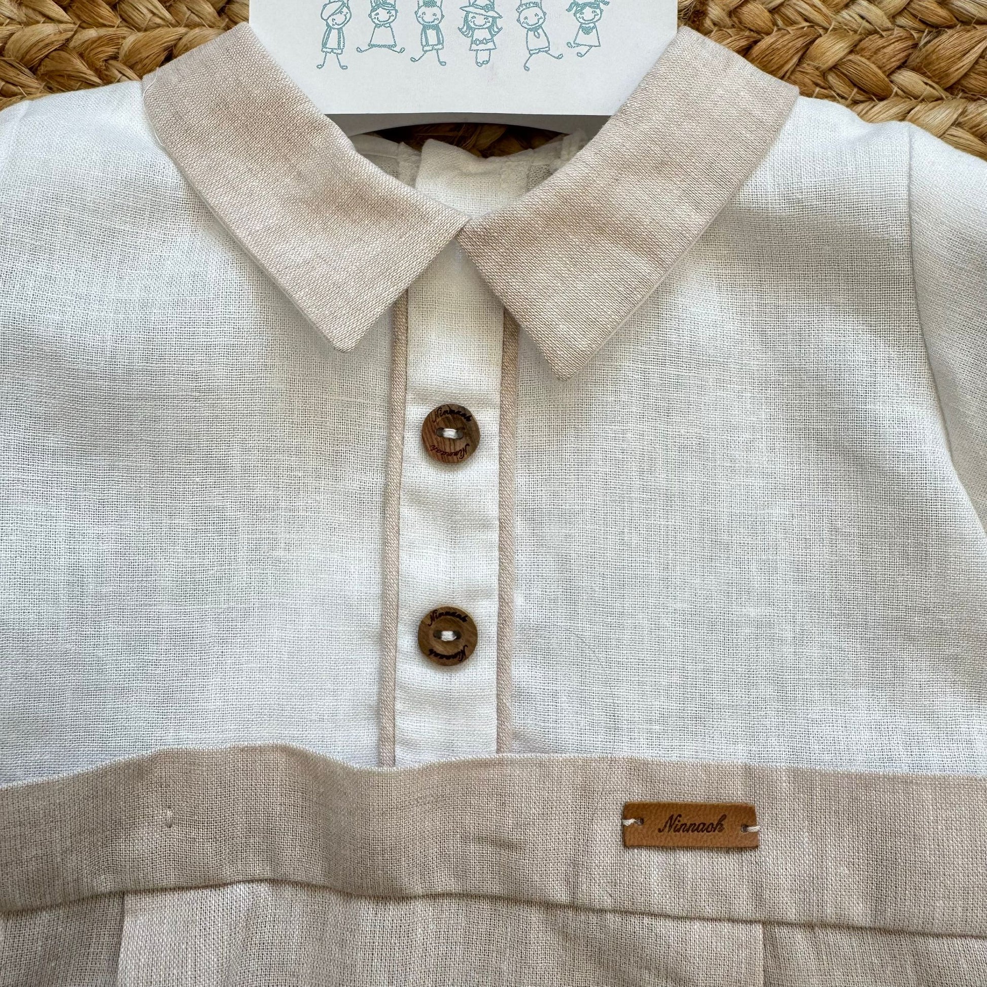 Dettaglio bottoni in legno e colletto profilato su tutina neonato elegante.