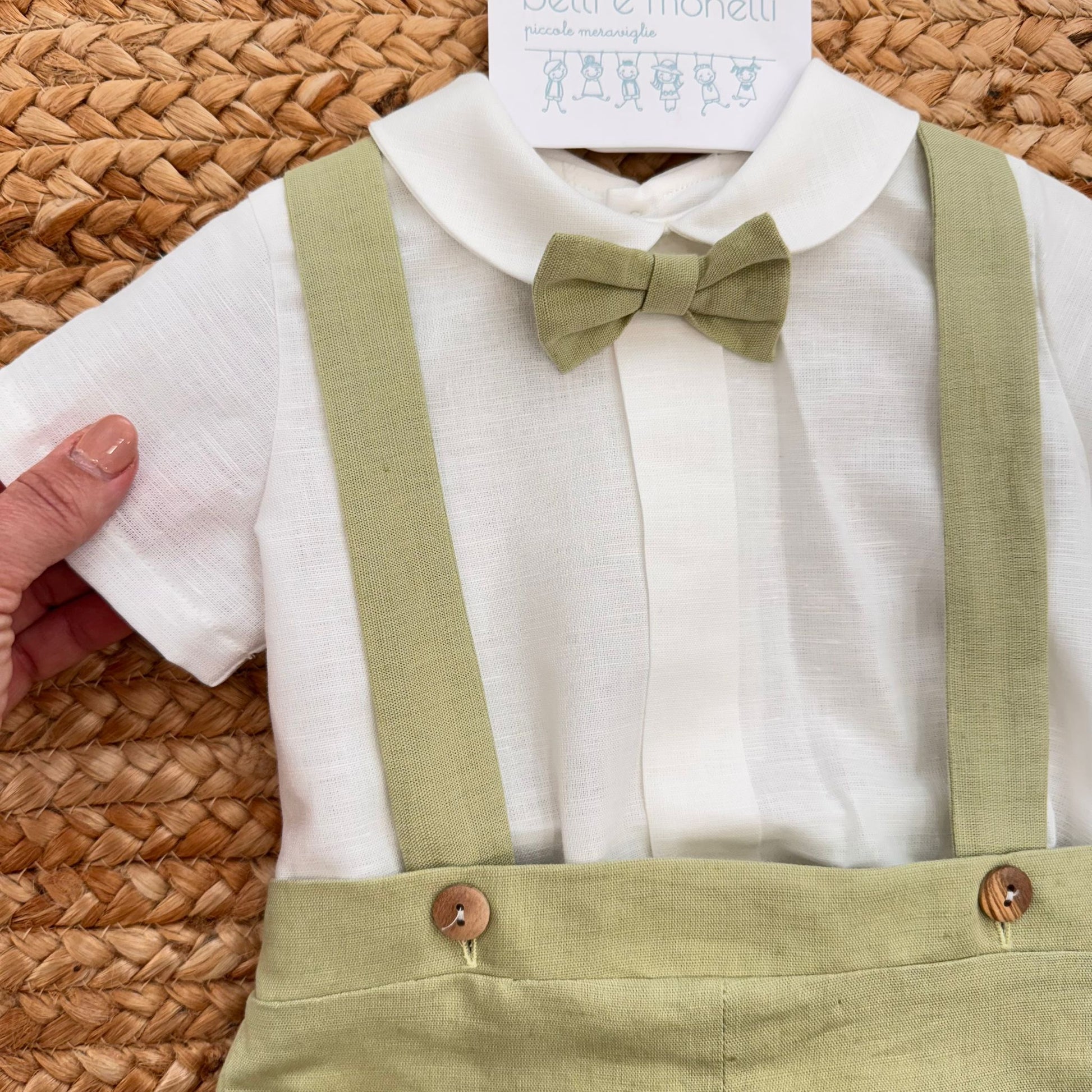 Dettaglio completo battesimo bimbo con camicia bianca e bretelle verde salvia
