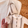 Primo piano su cappellino neonato e parte del completino in maglia con copertina coordinata panna e beige