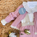 Dettaglio cardigan rosa in maglia per corredino neonata

