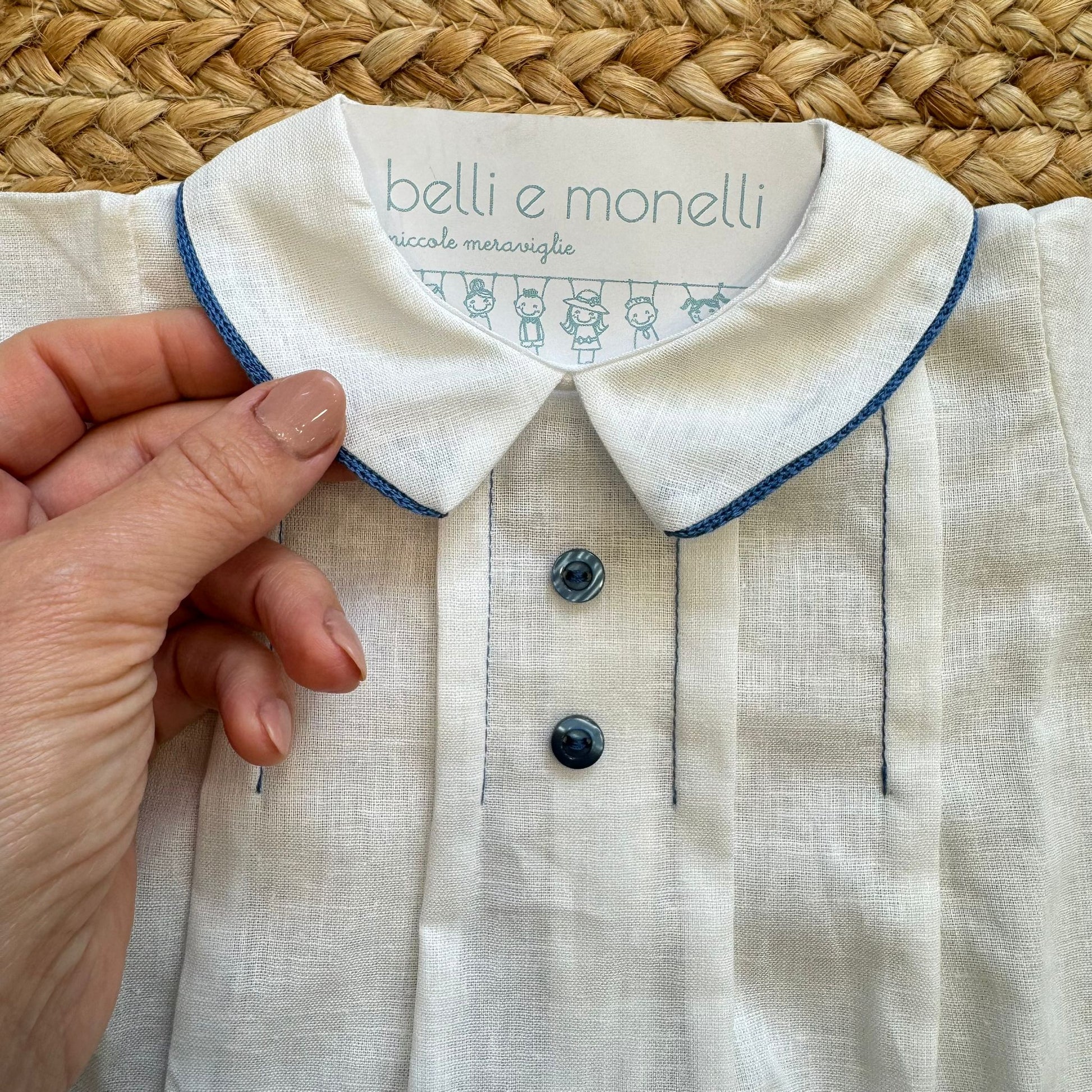 Dettaglio colletto bianco con profilo blu e bottoni frontali blu