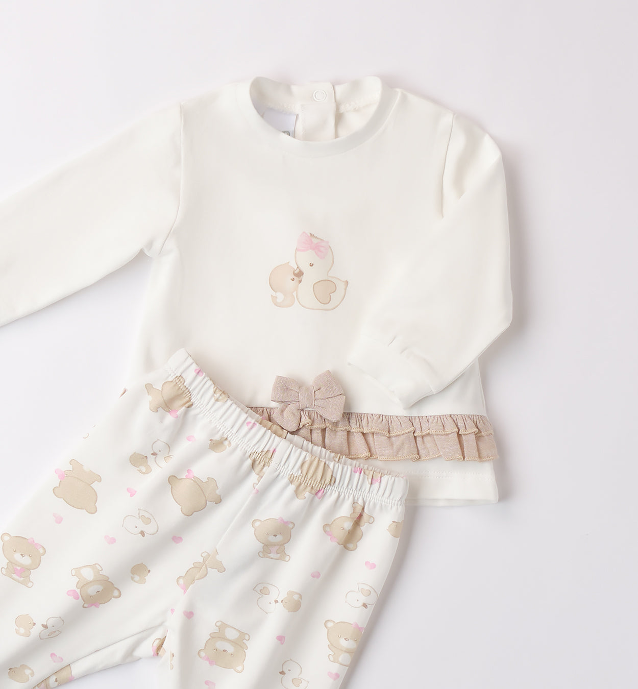 Dettaglio del completo neonata con fiocco e volant beige sulla maglia