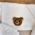 Dettaglio elegante del completo per neonato beige con scarpine e cappellino