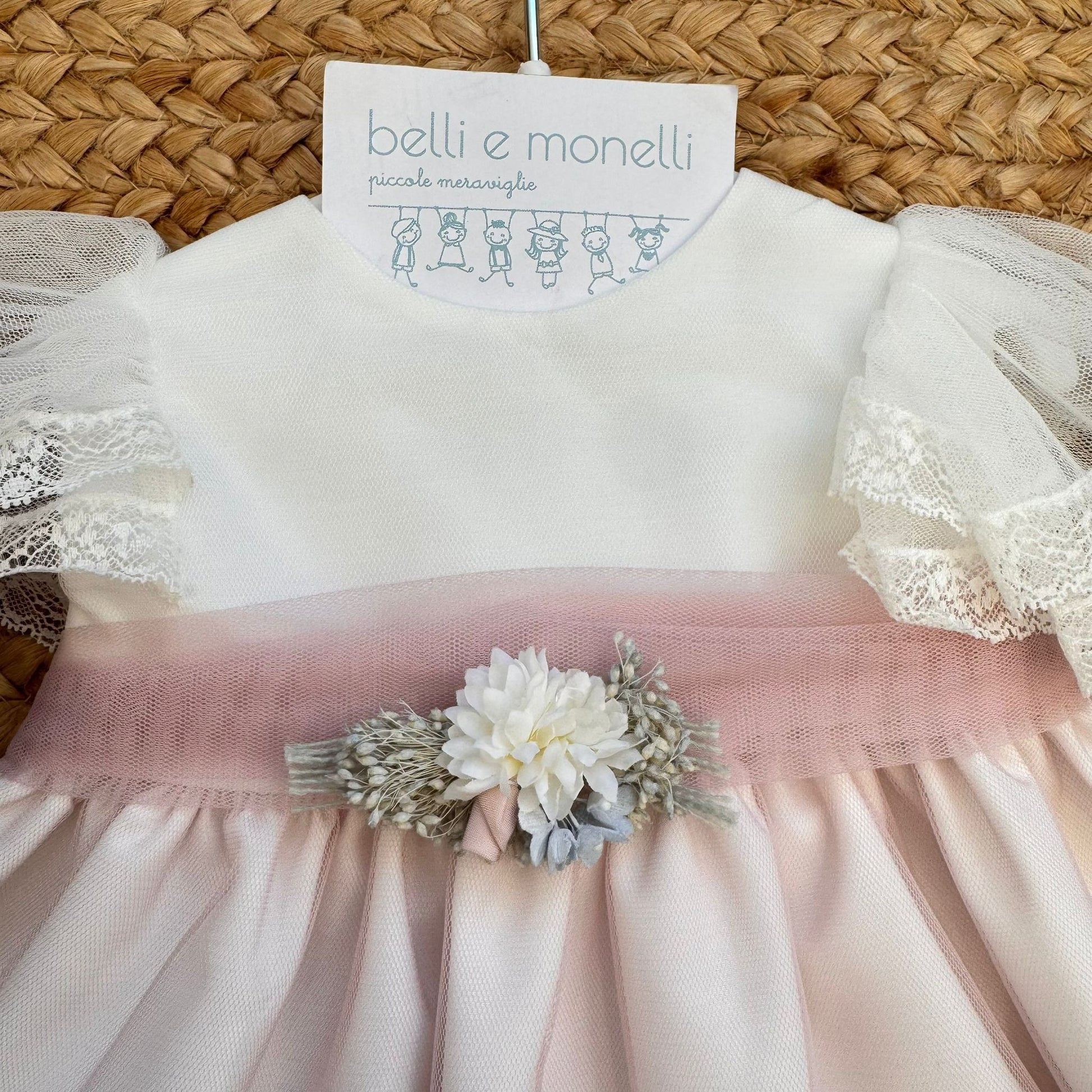 dettaglio corpino bianco con cintura rosa e applicazione floreale