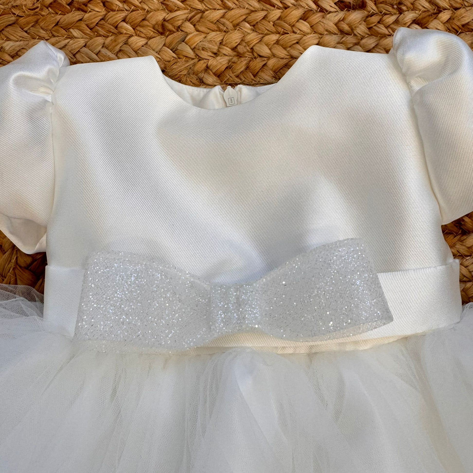 Dettaglio corpino bianco con fiocco glitter su abito battesimo bimba