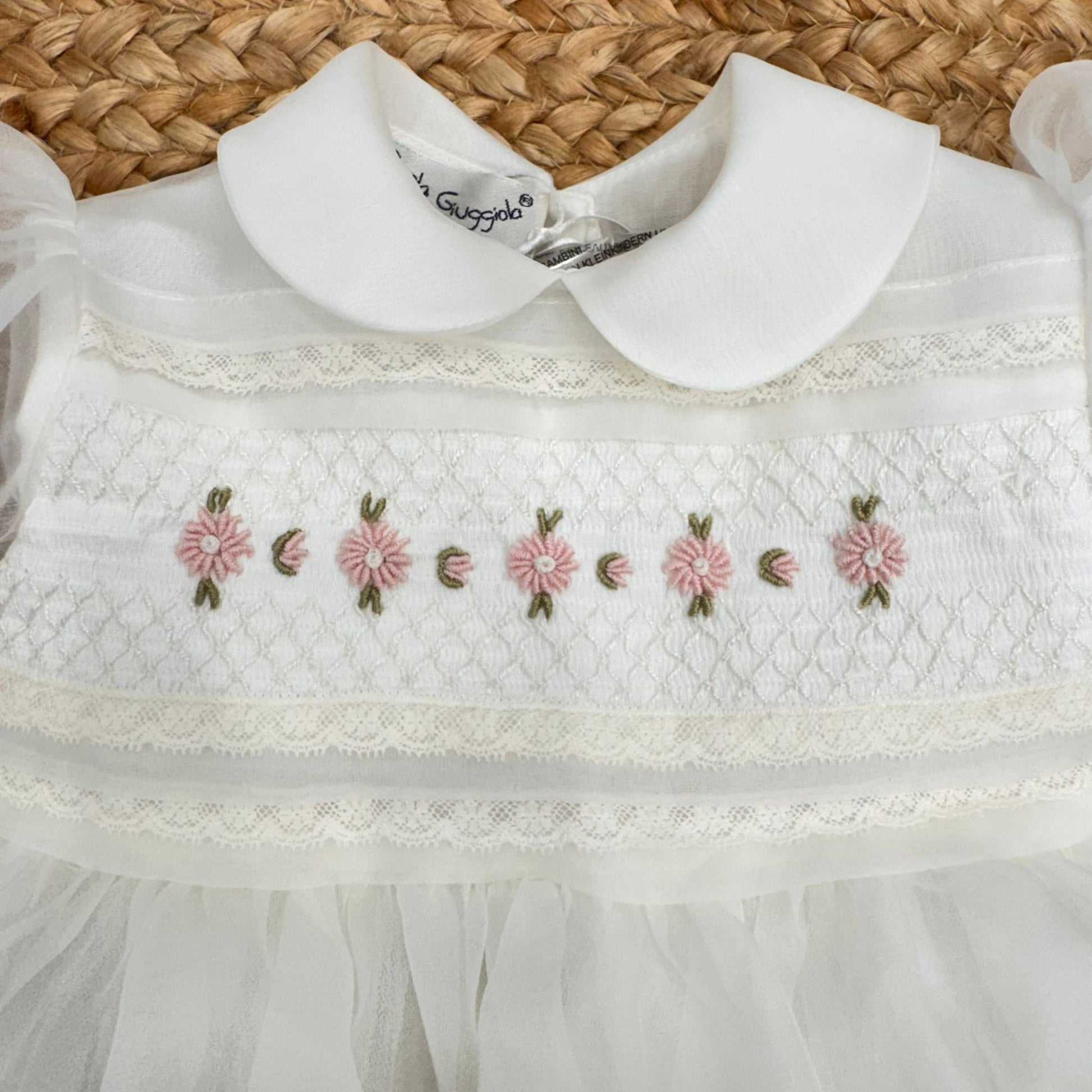Dettaglio corpino abito battesimo bimba con ricami artigianali floreali rosa e colletto tondo