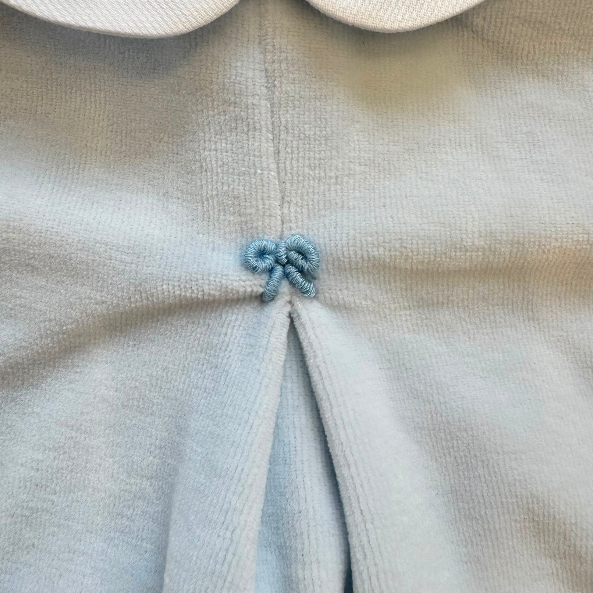 Tutina neonato in ciniglia color cielo con colletto bianco ricamato.