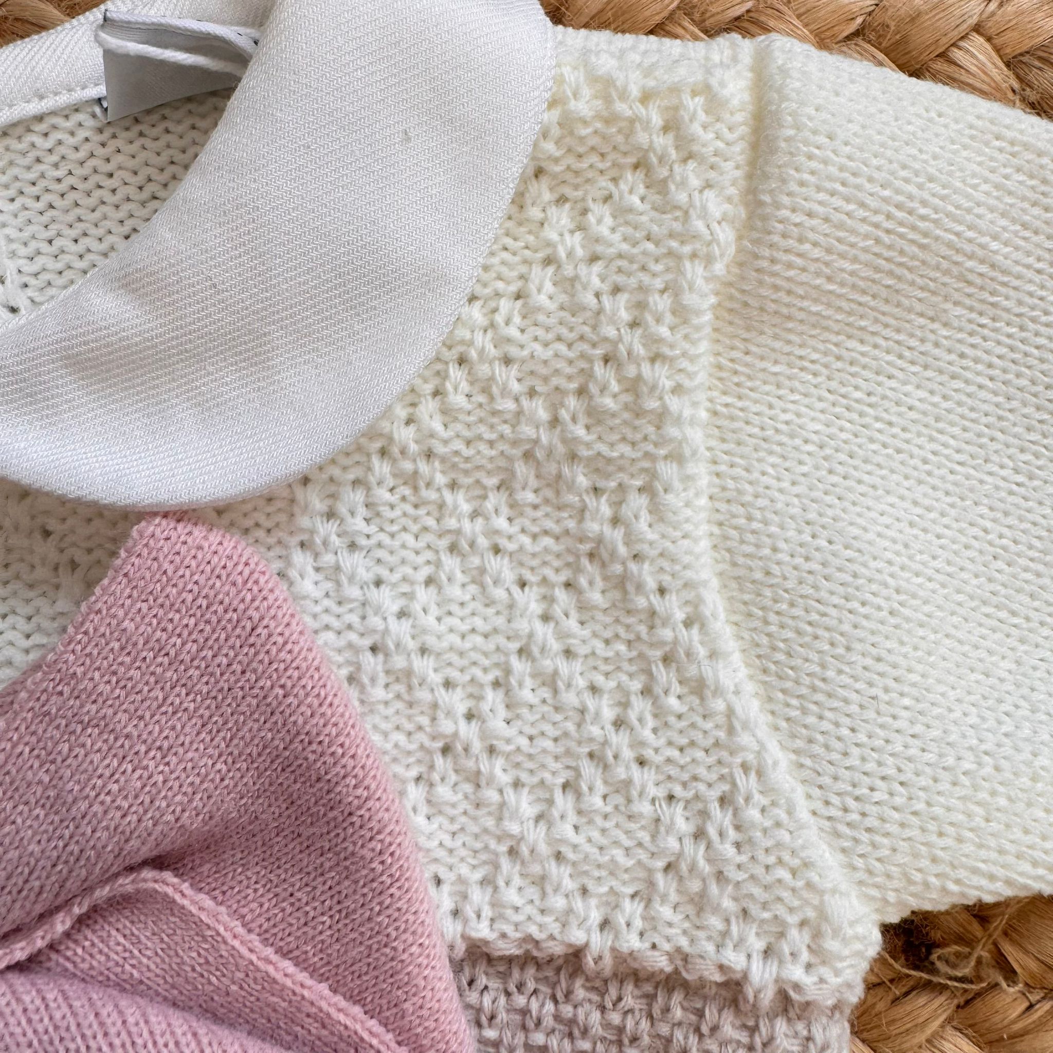 Dettaglio fiocco rosa in maglia e colletto bianco tondo sul completo neonata

