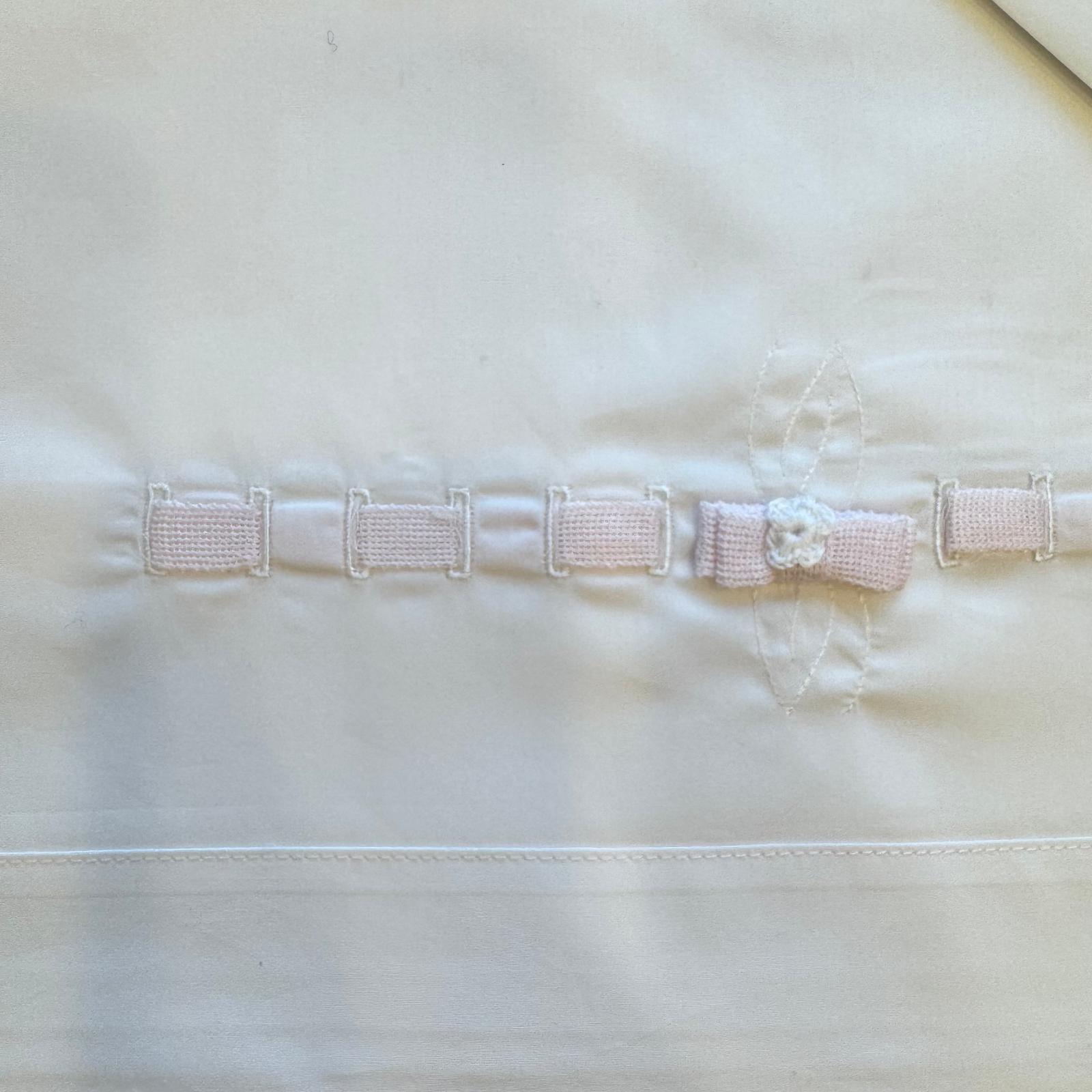 dettaglio fiocco rosa e passanastro su lenzuolo neonata