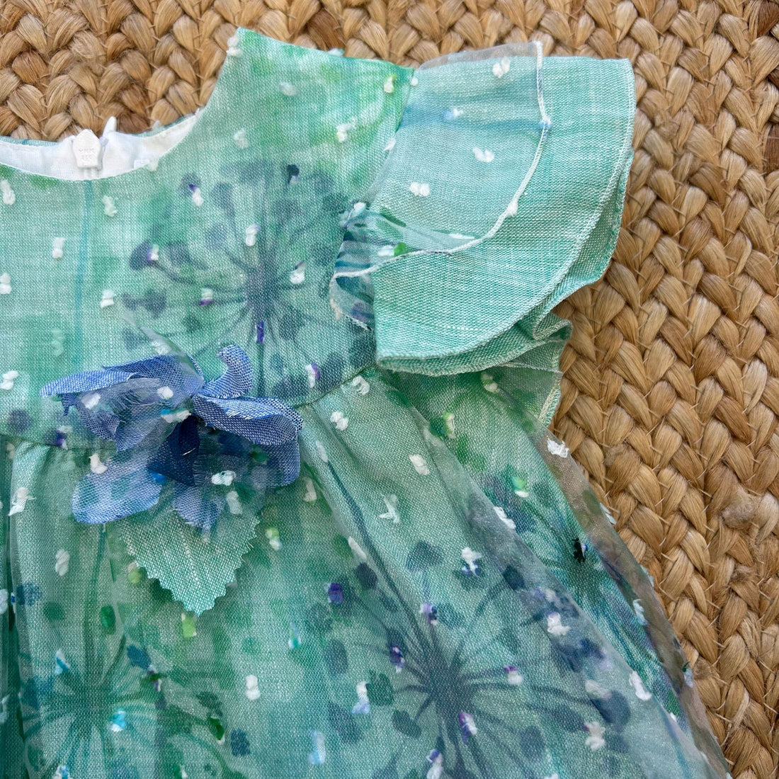 Vestito bambina verde salvia con fiori stampati, volant e fiocco blu

