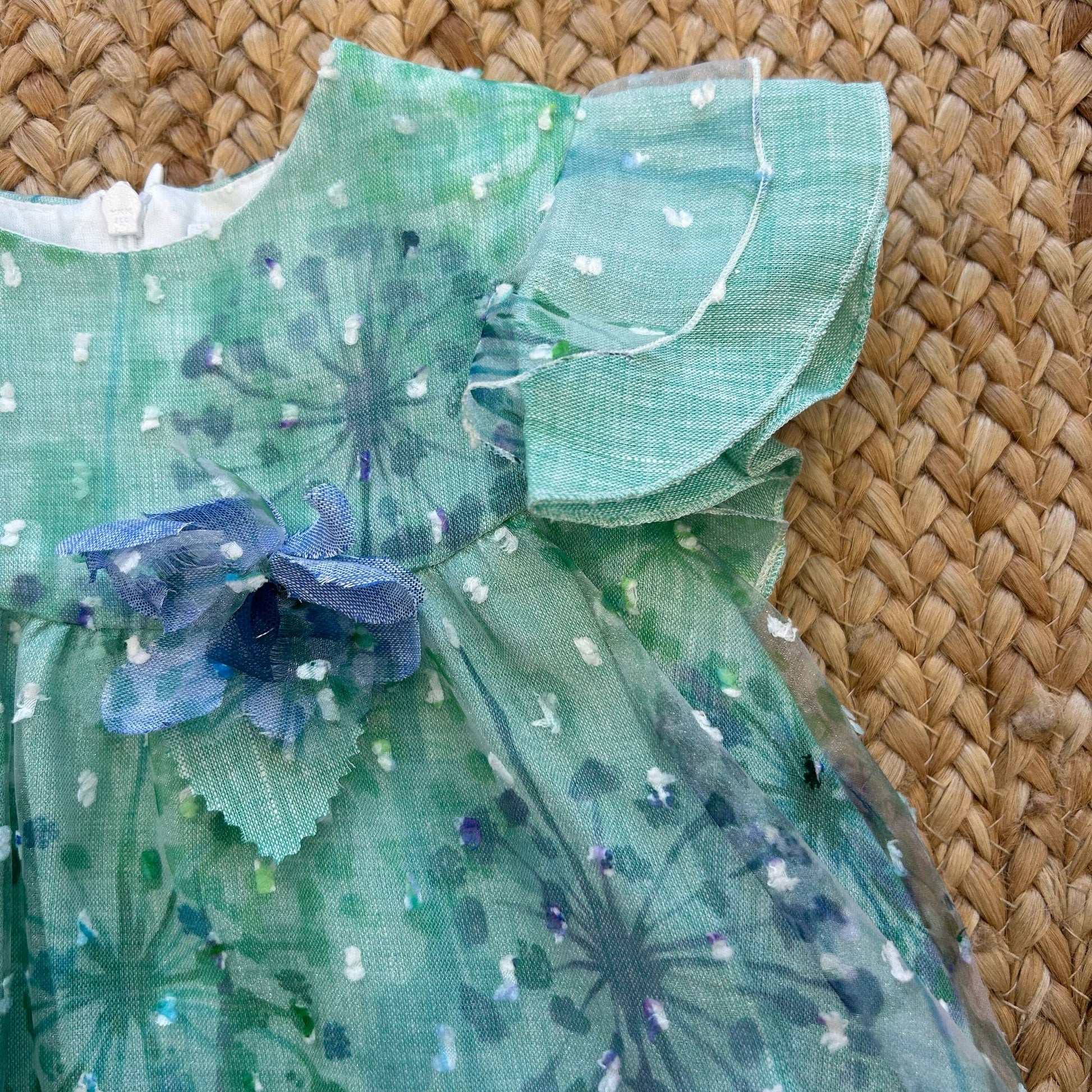 Vestito bambina verde salvia con fiori stampati, volant e fiocco blu

