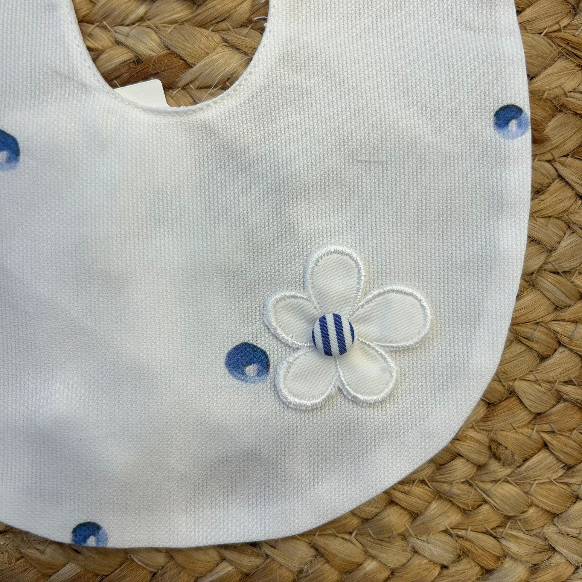 Dettaglio fiore ricamato su bavaglino bianco per neonata con pois
