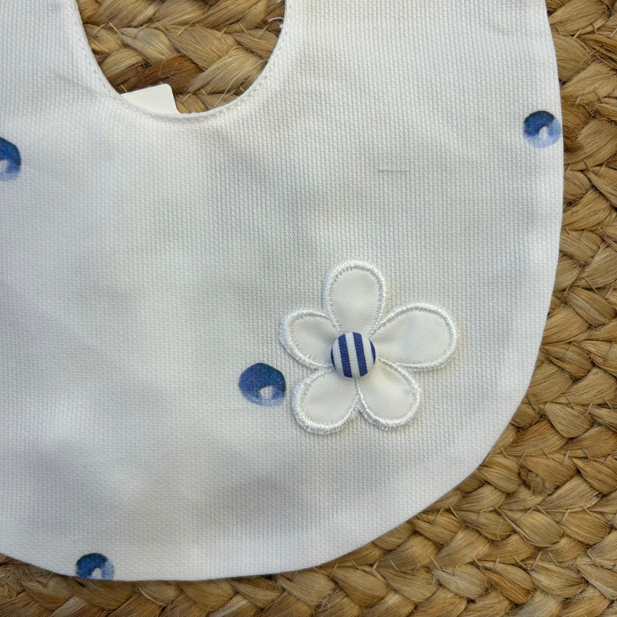 Dettaglio fiore ricamato su bavaglino bianco per neonata con pois
