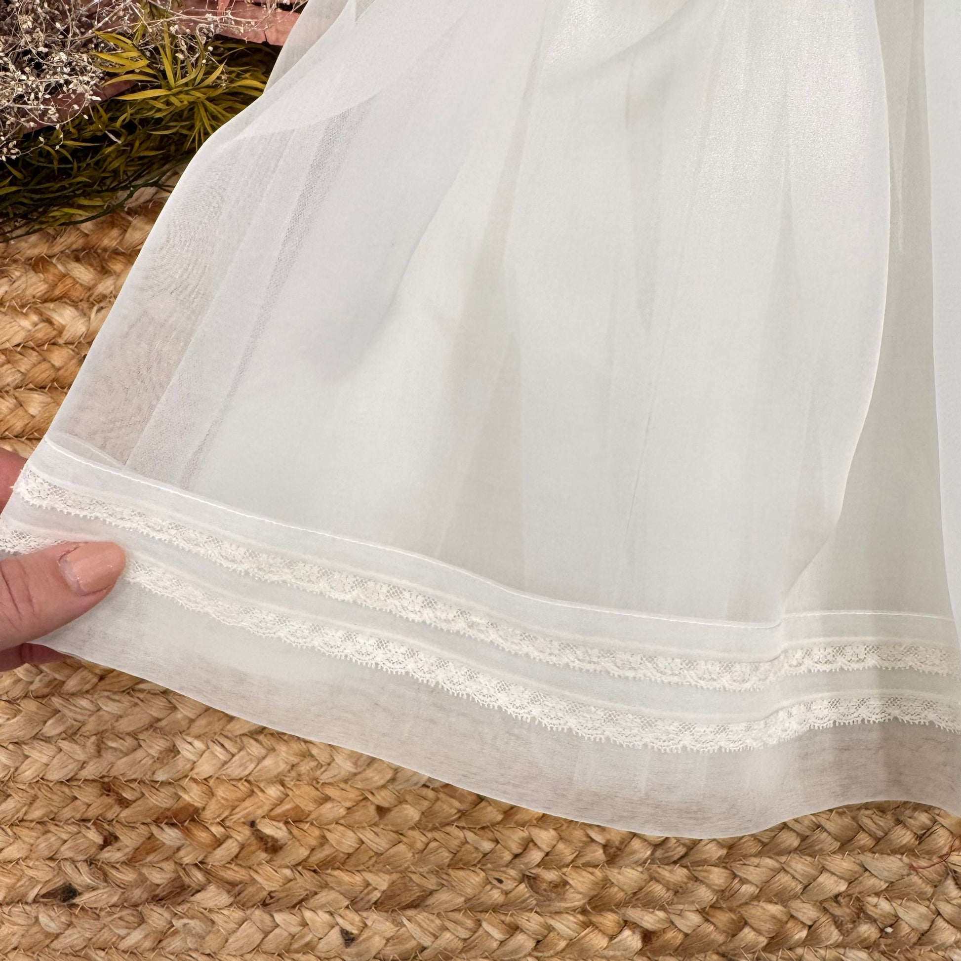 Dettaglio gonna abito battesimo bimba in organza di seta con rifiniture in pizzo sul fondo
