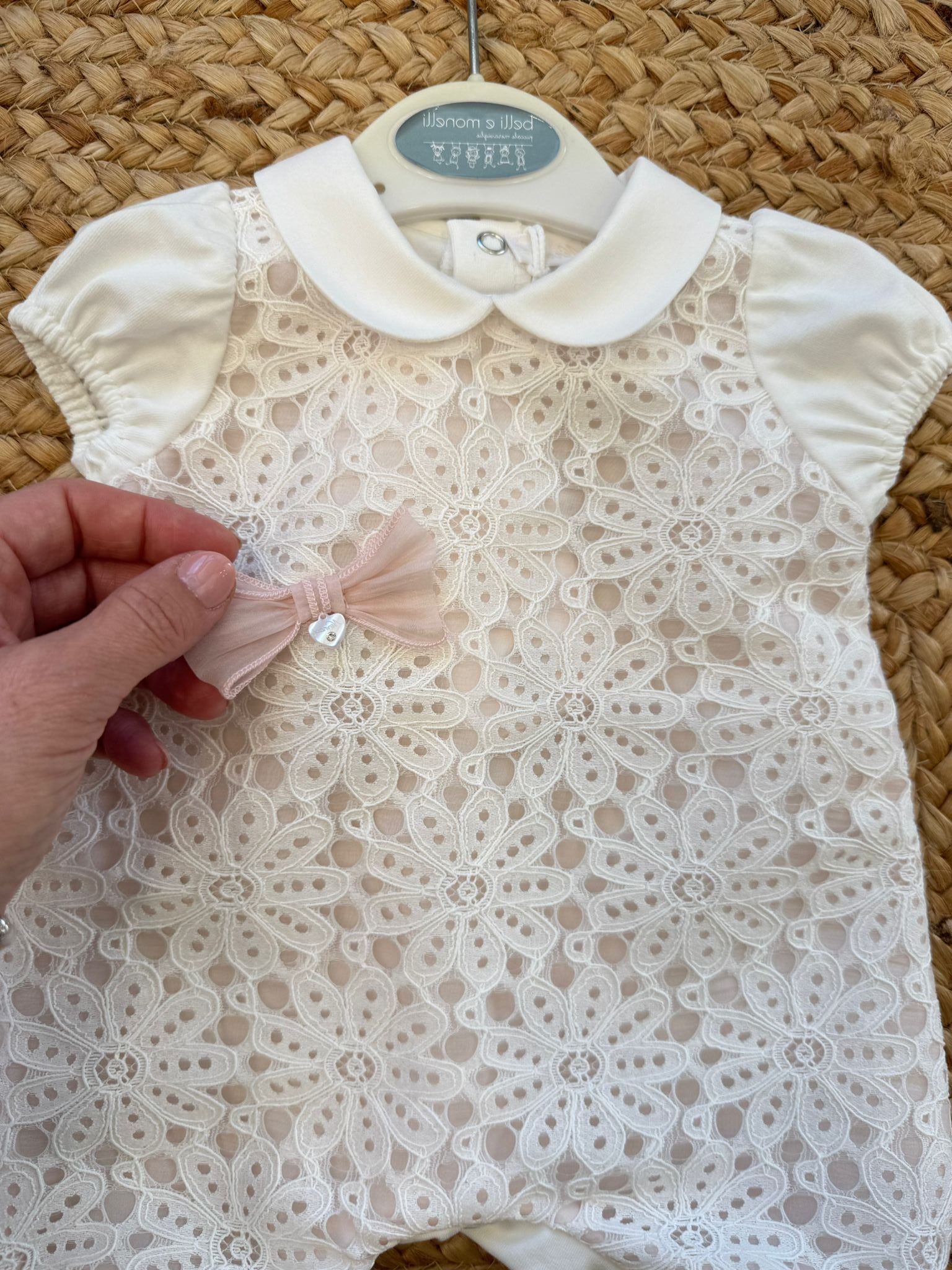 Dettaglio macramè floreale su tutina neonata