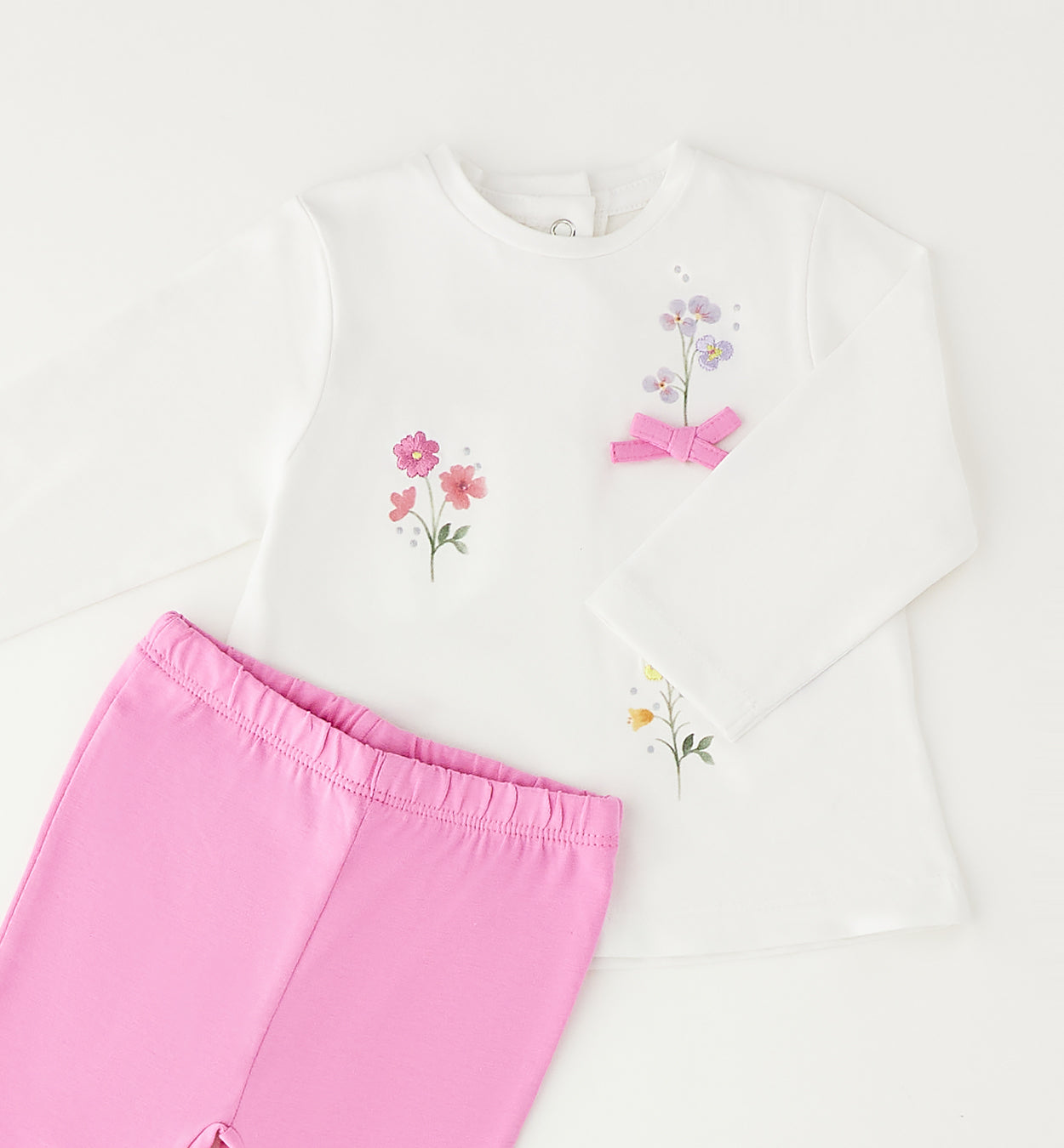 Dettaglio maglia bimba con ricami floreali e fiocco rosa