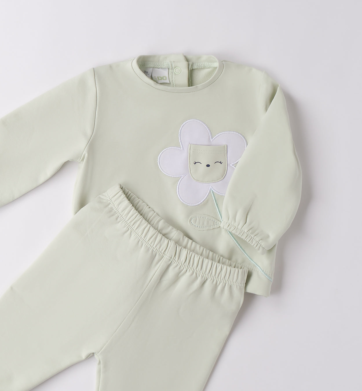 Dettaglio maglia con applicazione fiore e tasca centrale