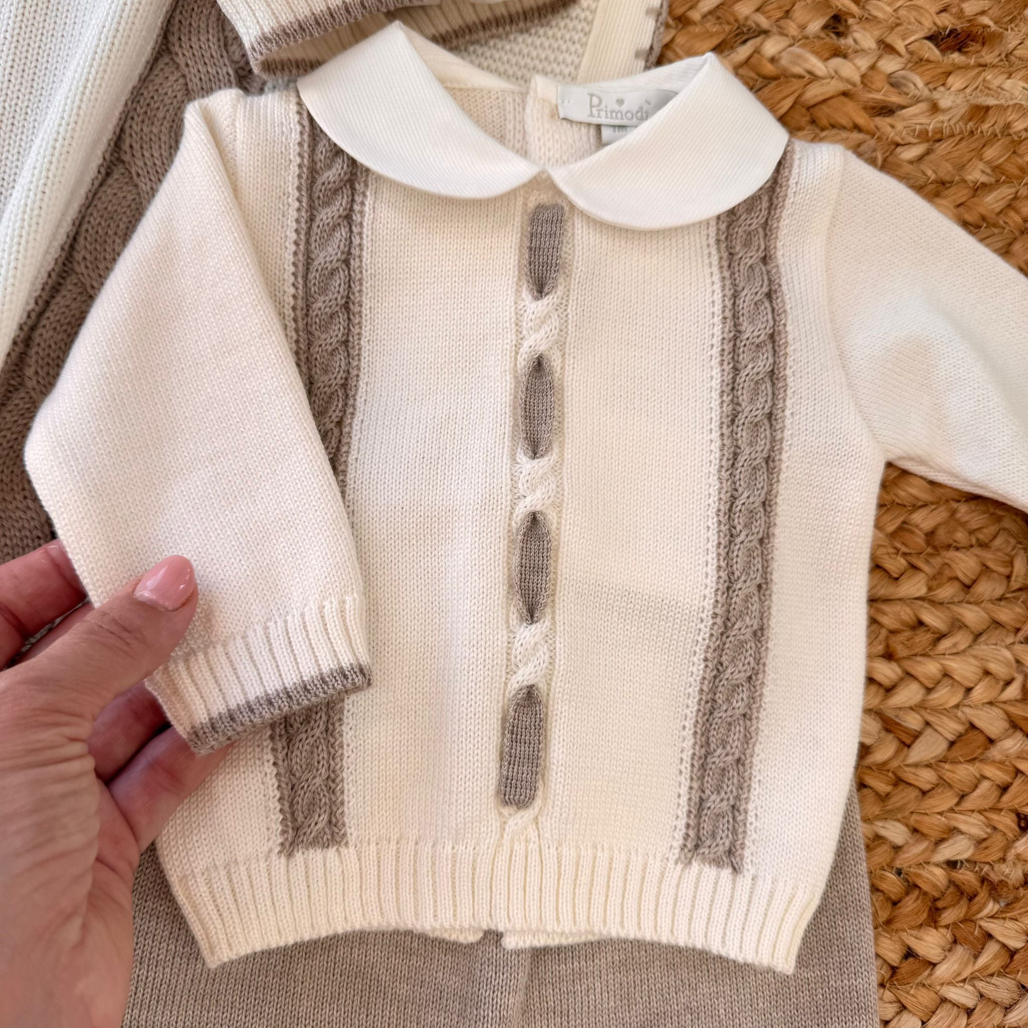 Zoom sul maglioncino panna con lavorazione trecce beige del completino caldo per neonato inverno