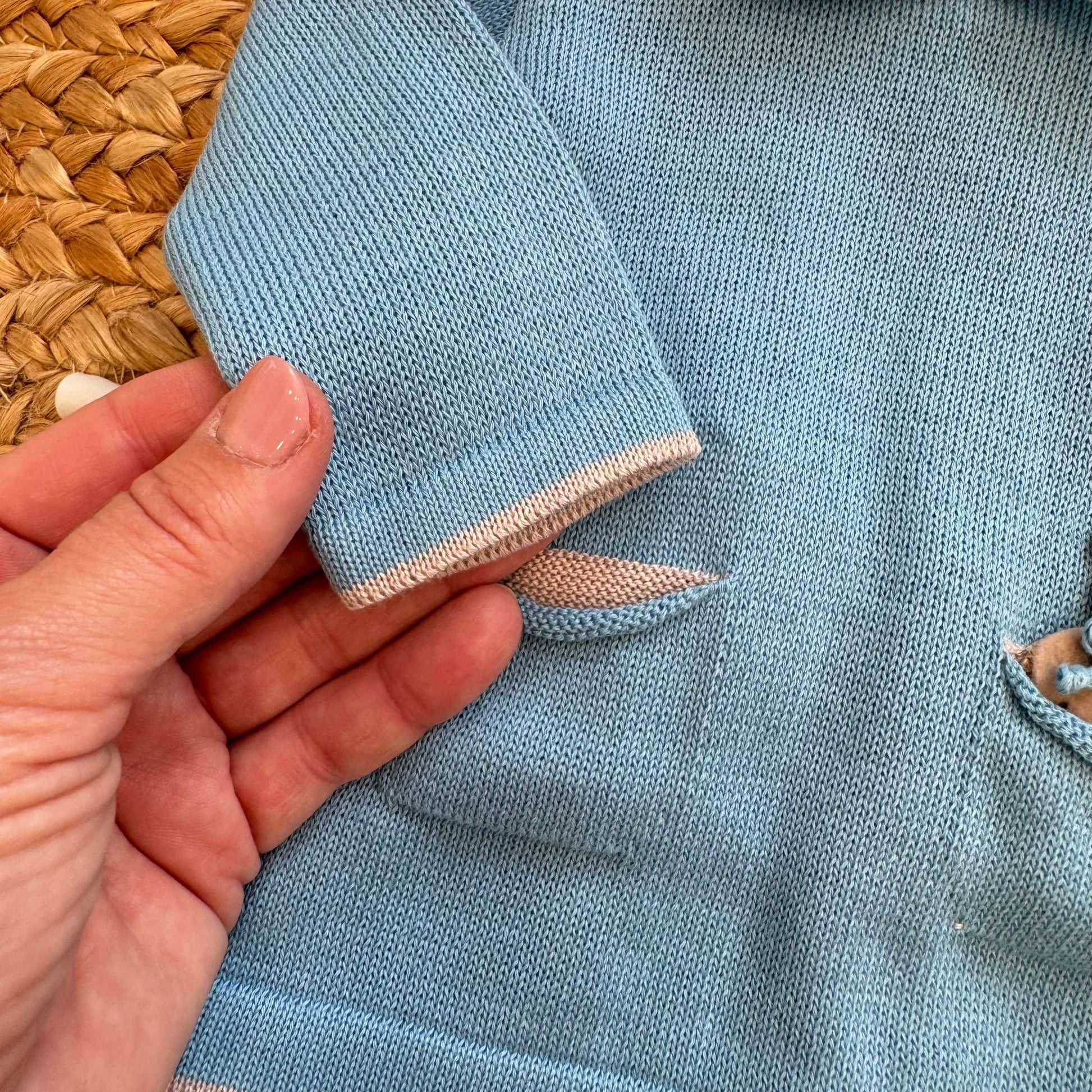 Dettaglio manica e rifiniture tutina neonato in filo di cotone