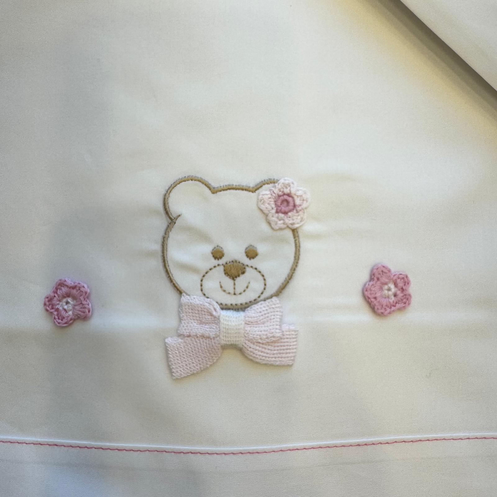 dettaglio orsetto ricamato con fiocco e applicazioni rosa su lenzuolino neonata