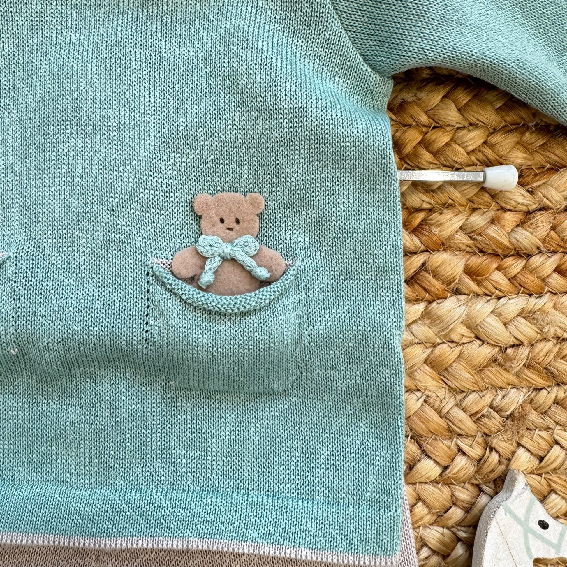 Dettaglio taschino con orsetto su tutina neonato verde