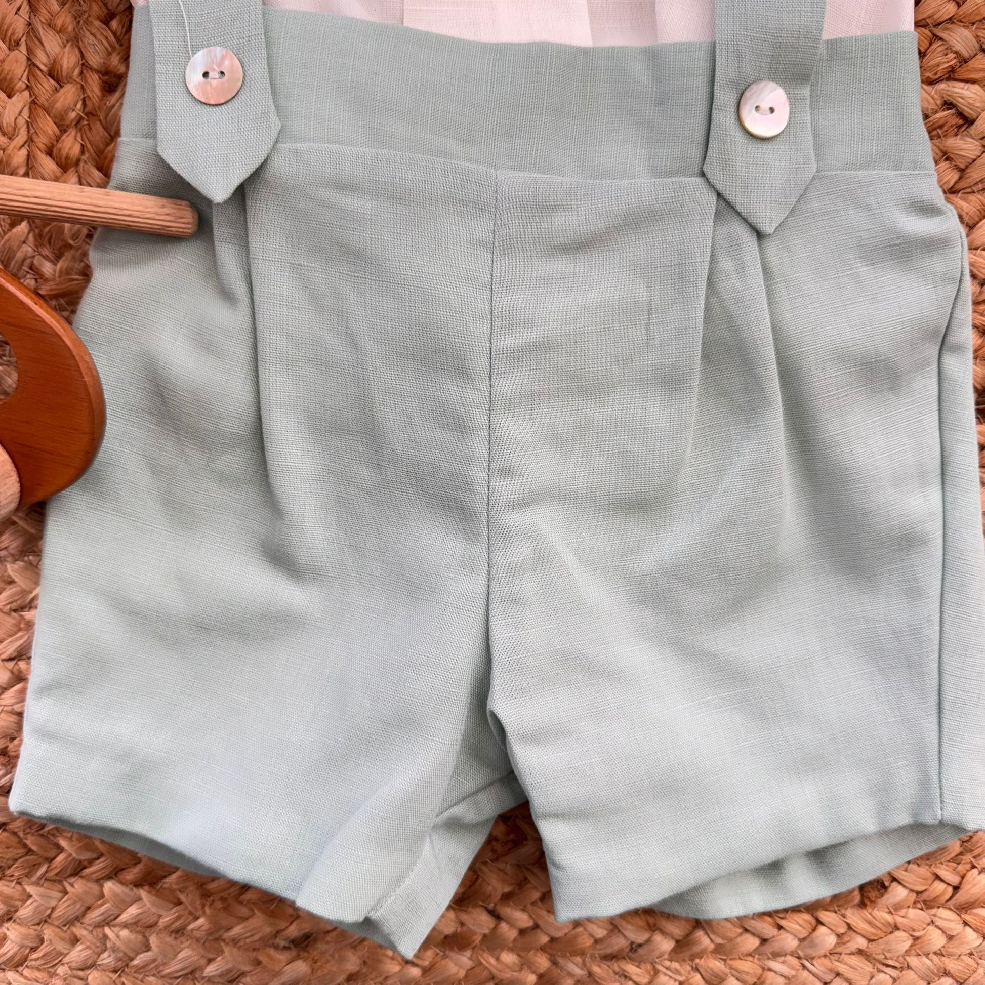 Dettaglio pantaloncino verde salvia con bretelle e bottoni frontali decorativi