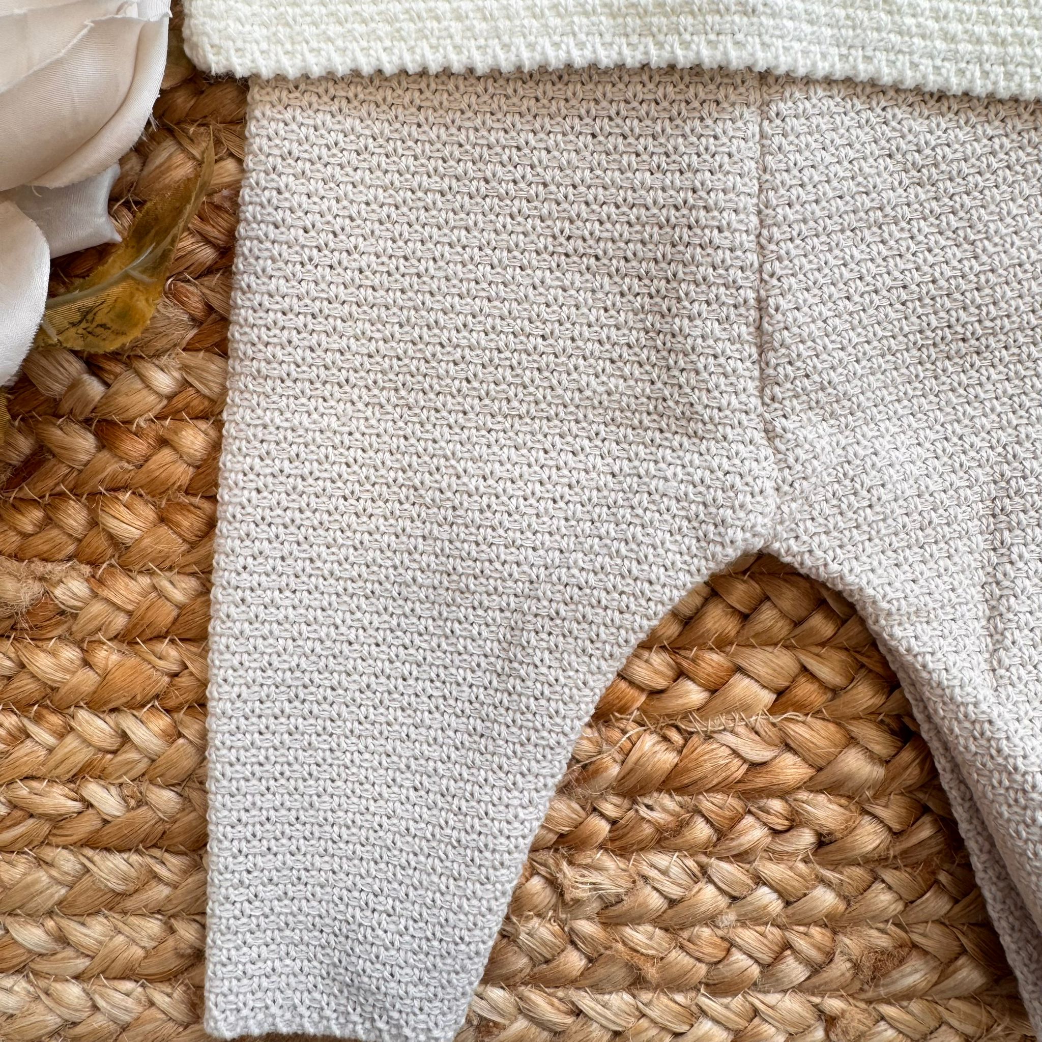 Dettaglio pantalone in maglia beige chiaro, lavorazione punto riso per neonata

