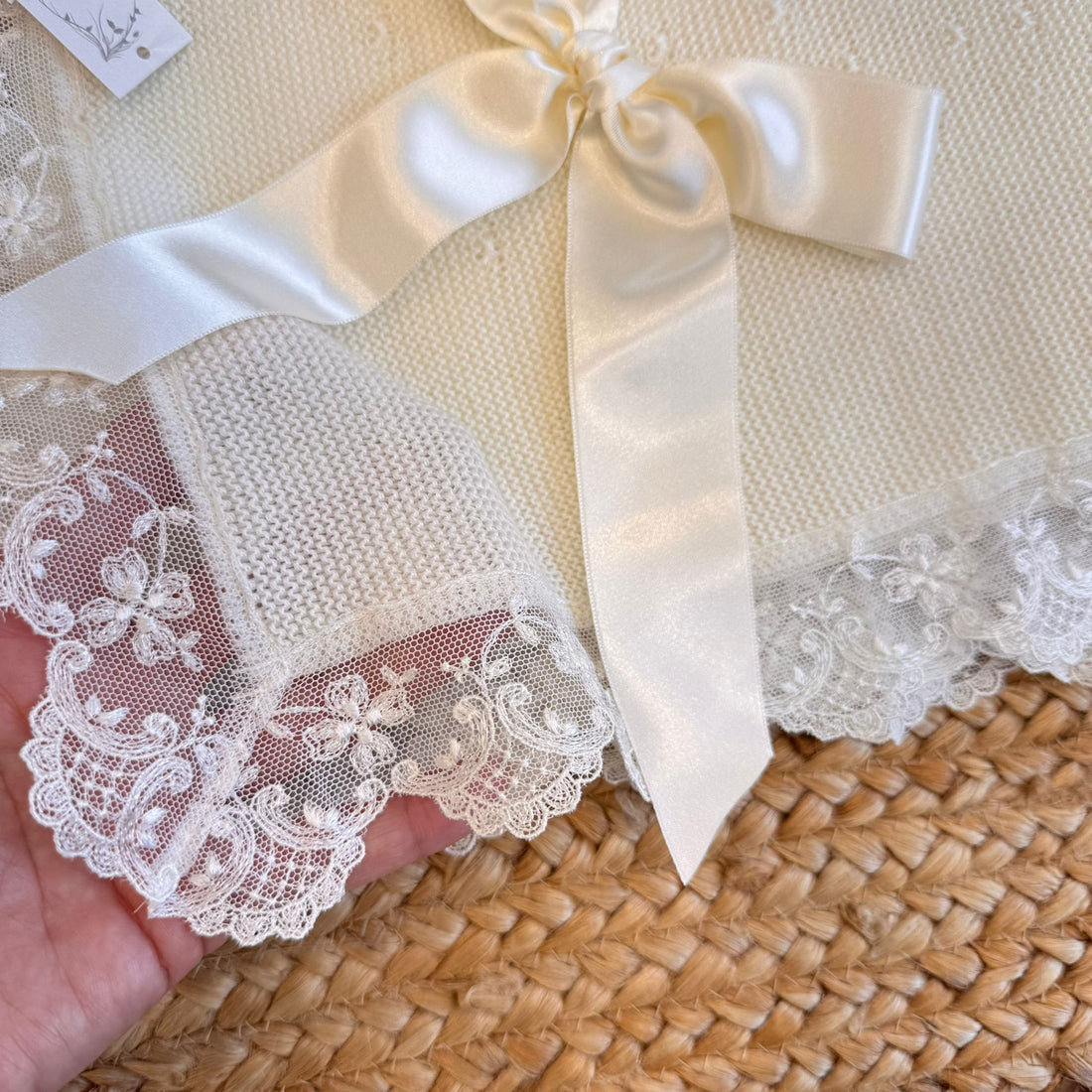 Copertina da battesimo in maglia panna con pizzo e fiocco in raso.