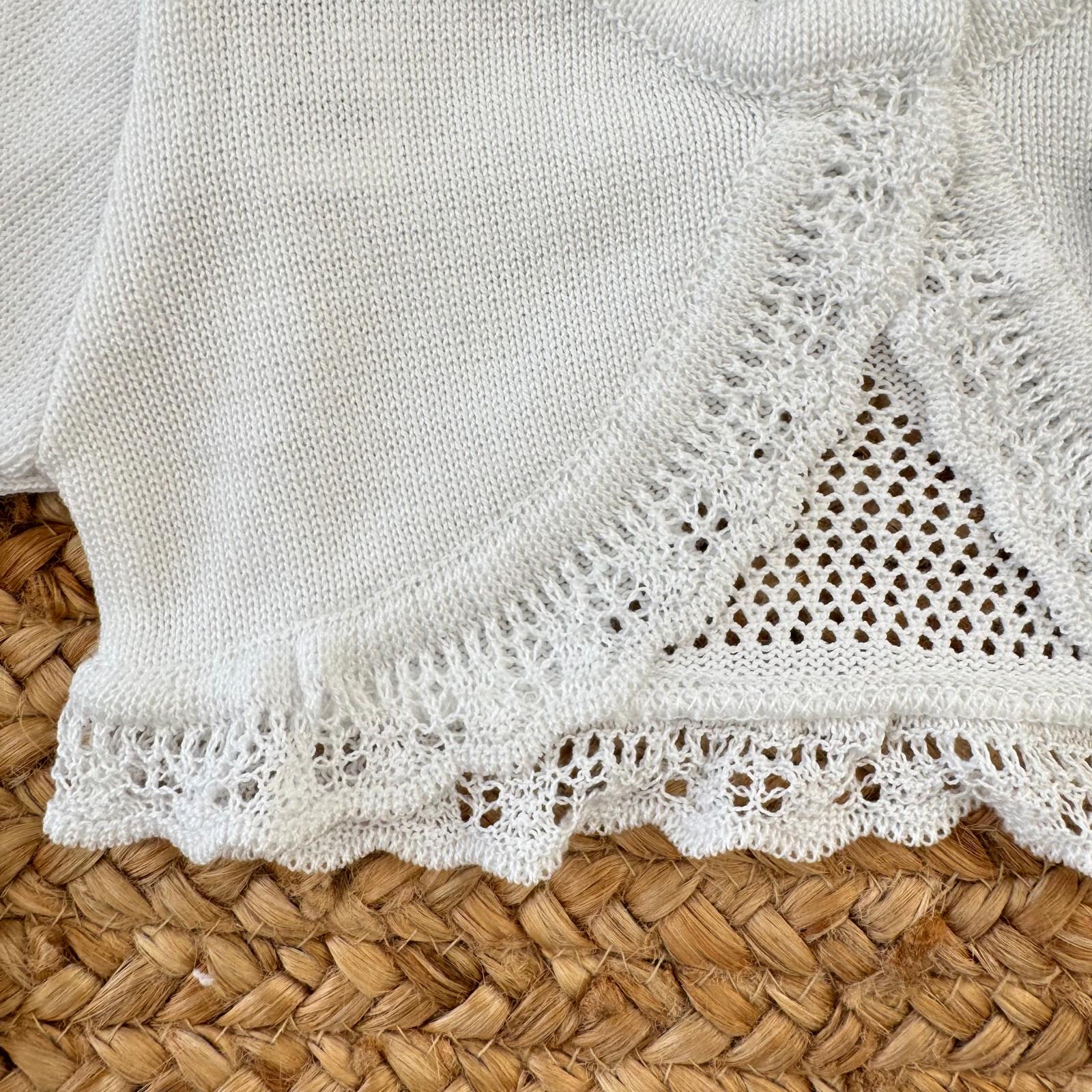 Dettaglio lavorazione traforata e pizzo coprispalle bianco neonata