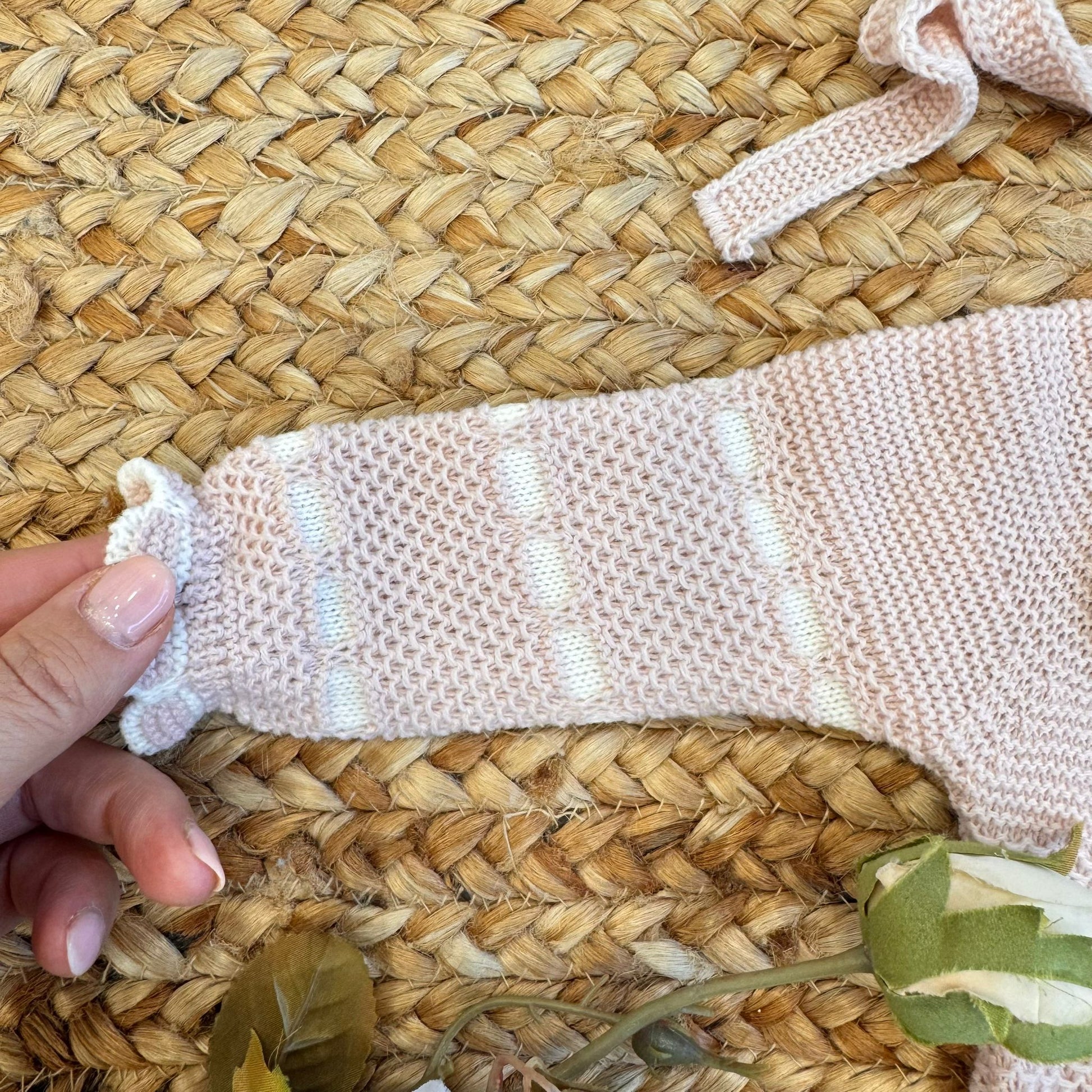 Dettaglio pompon panna su completo in maglia rosa