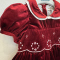 Abito bimba in velluto bordeaux con punto smock, colletto bianco a contrasto e maniche a palloncino.